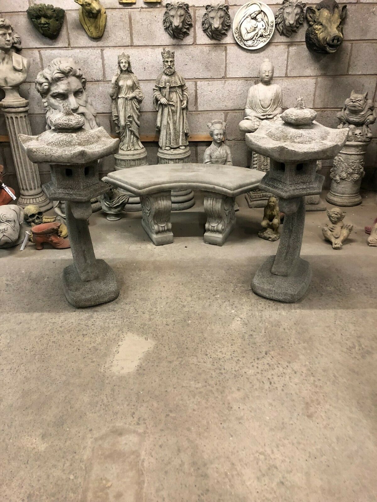 Set of two stone pagoda lantern statues displayed in a sculpture workshop, perfect for unique garden or patio decoration.