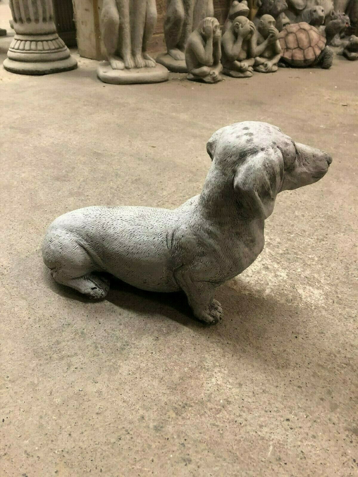 Angled side view of Stone Sausage Dog Garden Sculpture, perfect for outdoor decoration with antique weatherproof finish.