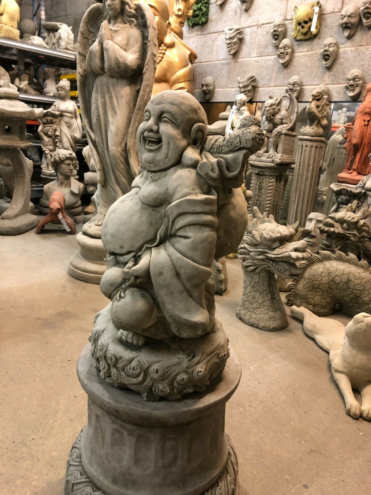 Angled view of Laughing Buddha Statue - Stone Plinth | Limestone Finish, ideal for enhancing garden spaces with a symbol of joy and prosperity.