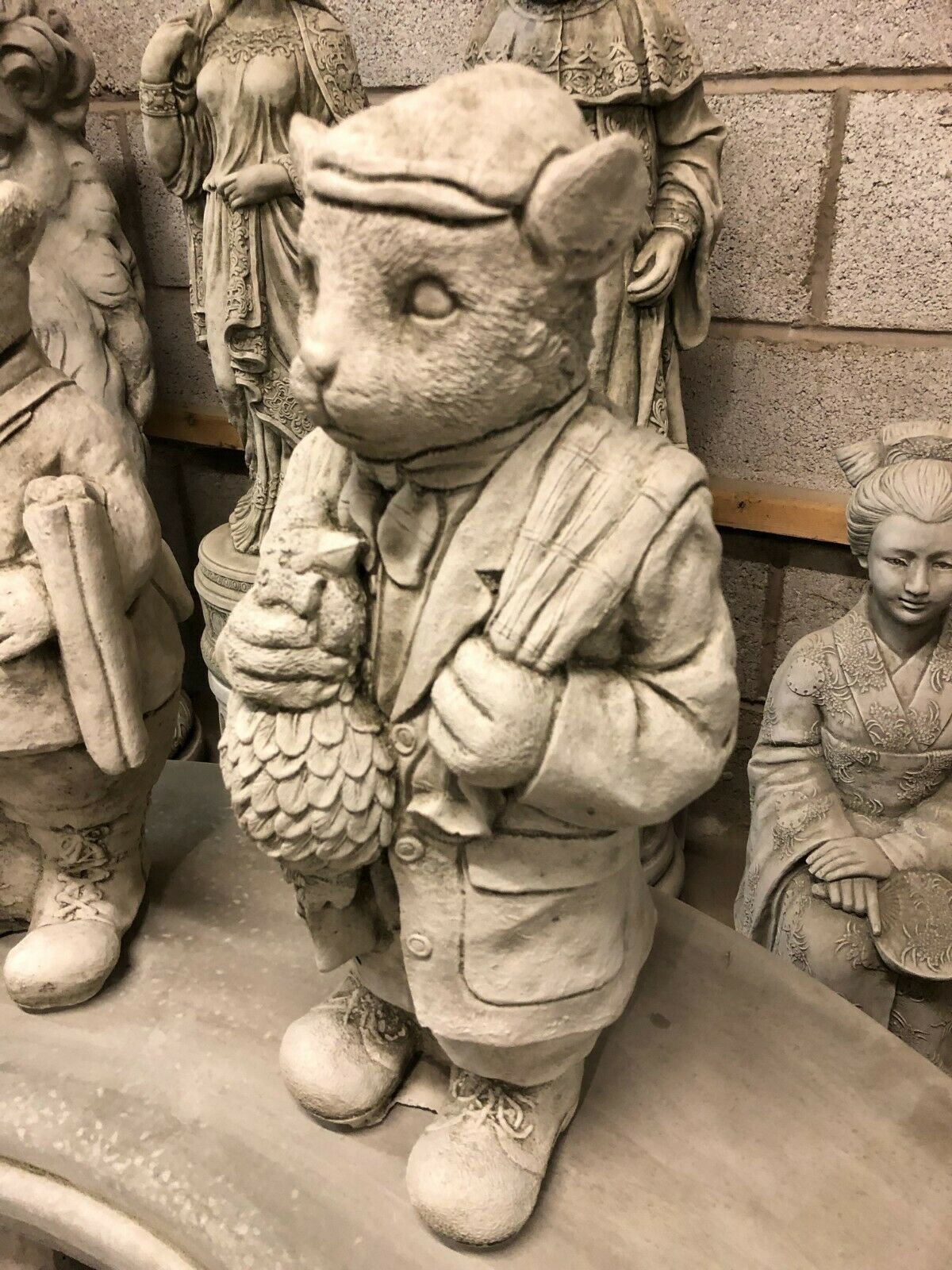Side view of gamekeeper statue from Stone Gamekeeper & Poacher Statues-Garden Decor | Solid & Durable. Holding a bird and bag, ideal for outdoor display.