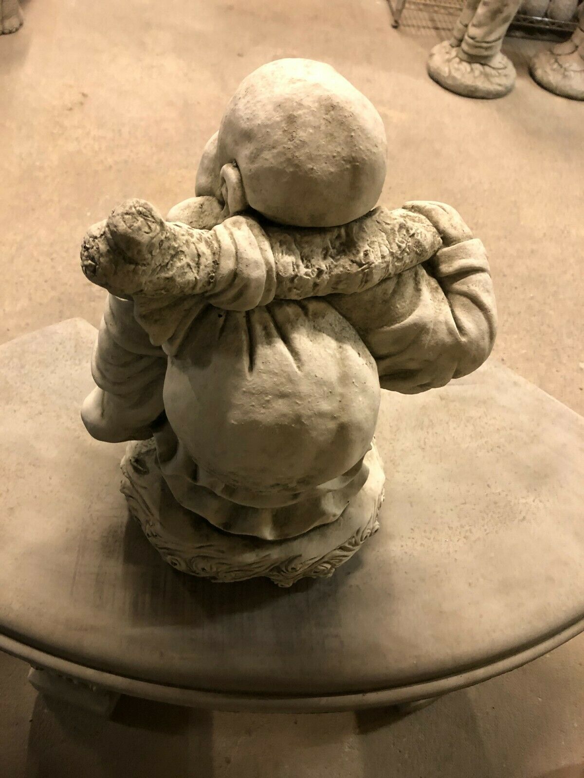Rear view of Stone Laughing Buddha Statue with antique stone finish, showcasing sack over shoulder and robe folds, suitable for outdoor ornamentation.