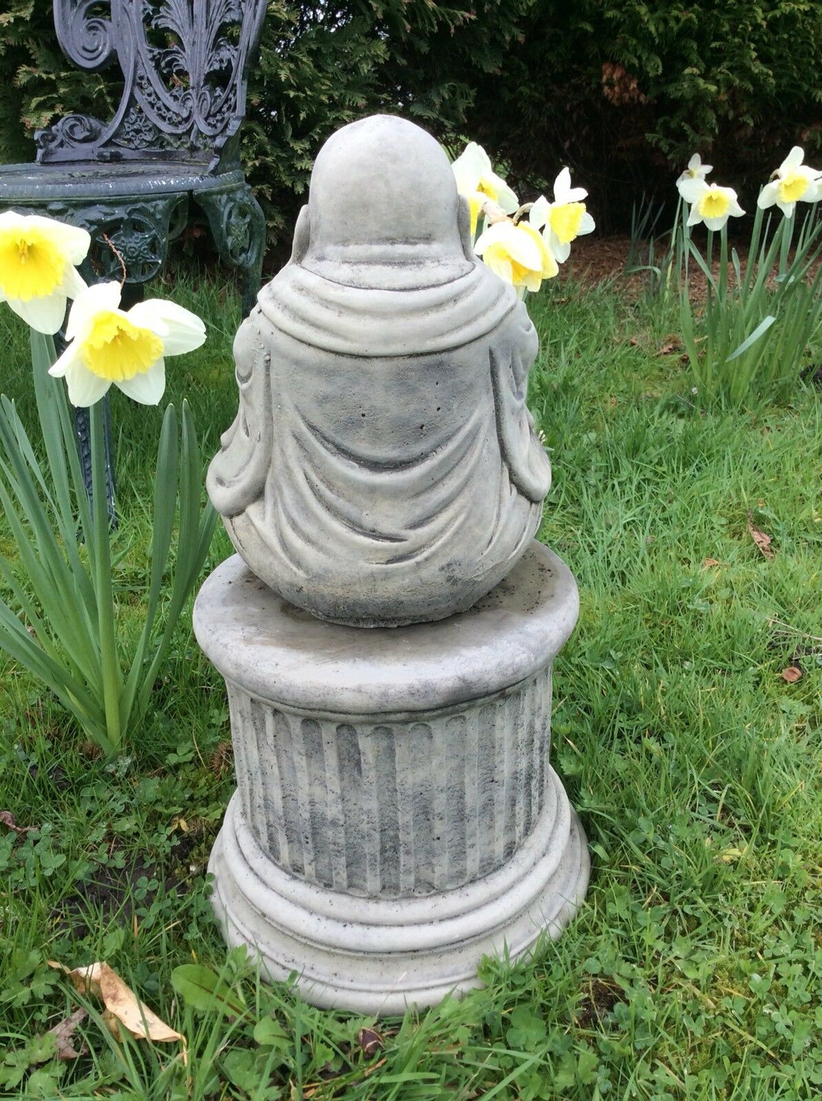 Rear view of stone Buddha statue showing detailed robe folds, placed on a classic pedestal, crafted for garden decor with antique charm.