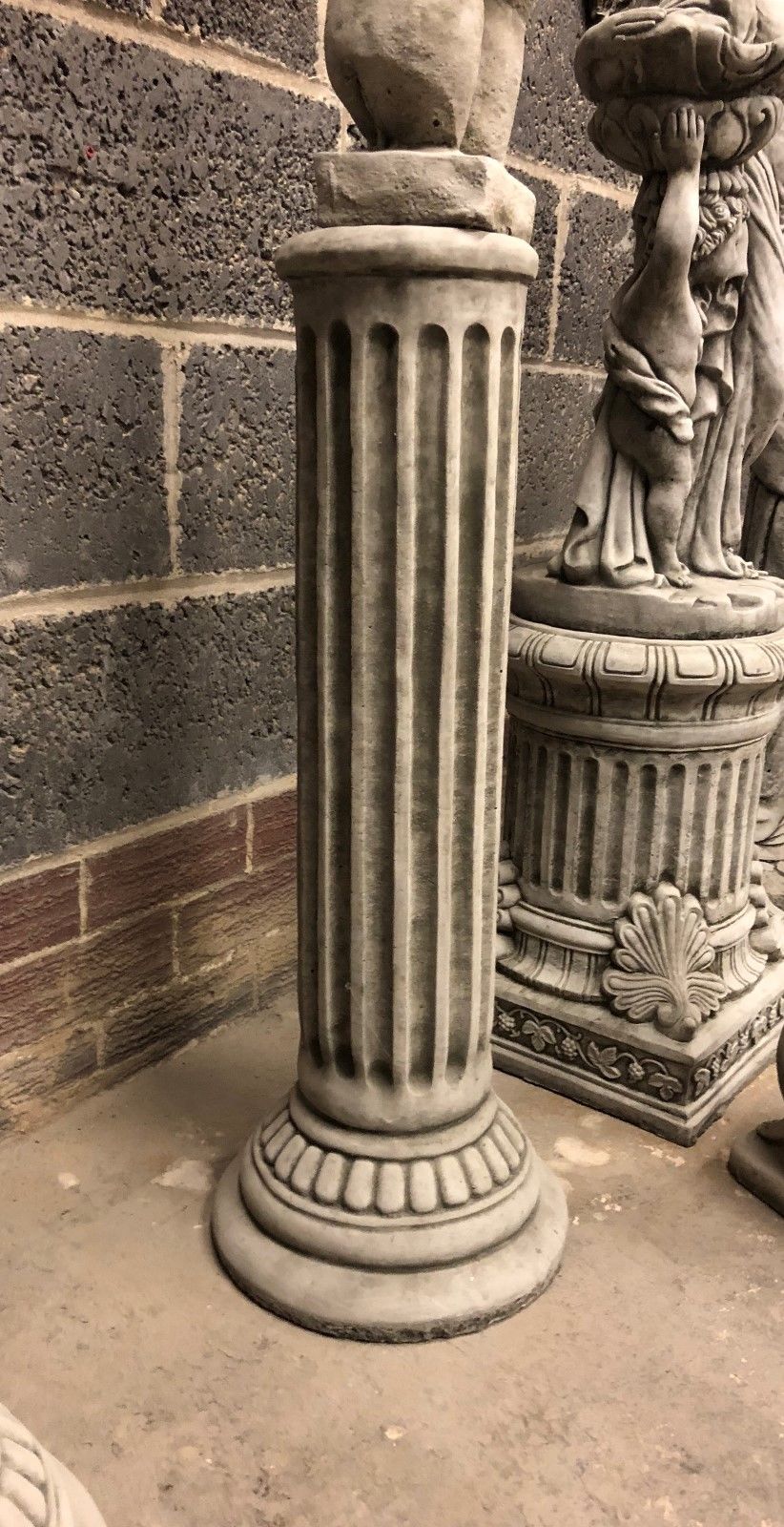Detailed view of limestone plinth with vertical grooves and antique finish. Perfect for supporting torso sculptures in outdoor decor.