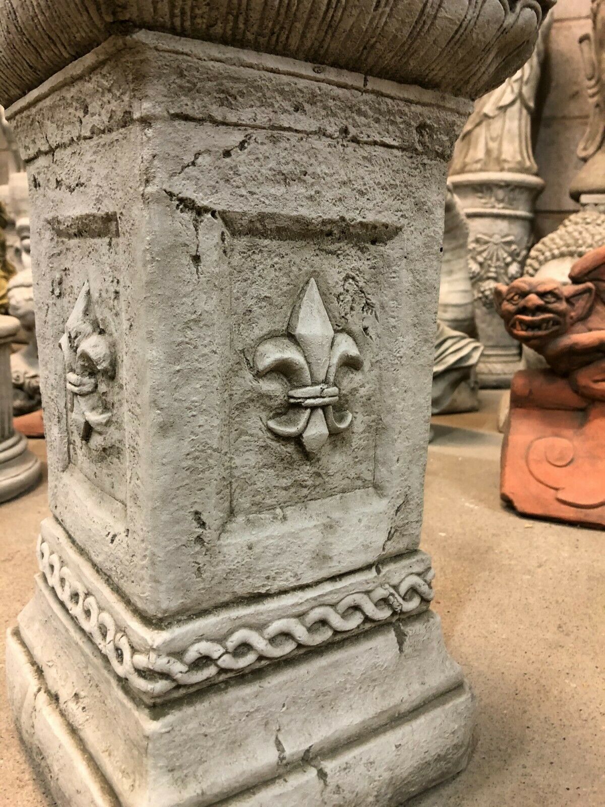 Close-up of Stone Fleur De Lis Pedestal showing detailed fleur-de-lis and rope carvings. Made from solid limestone for outdoor durability.