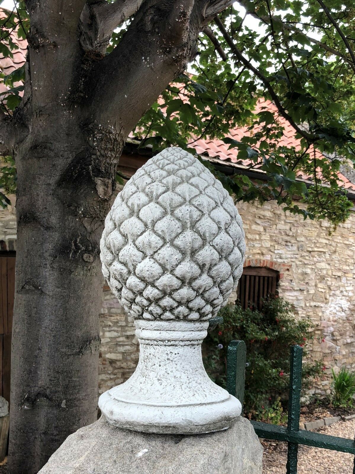 Decorative Stone Pineapple Finial placed on a gatepost, perfect for outdoor use with classic antique stone appearance.