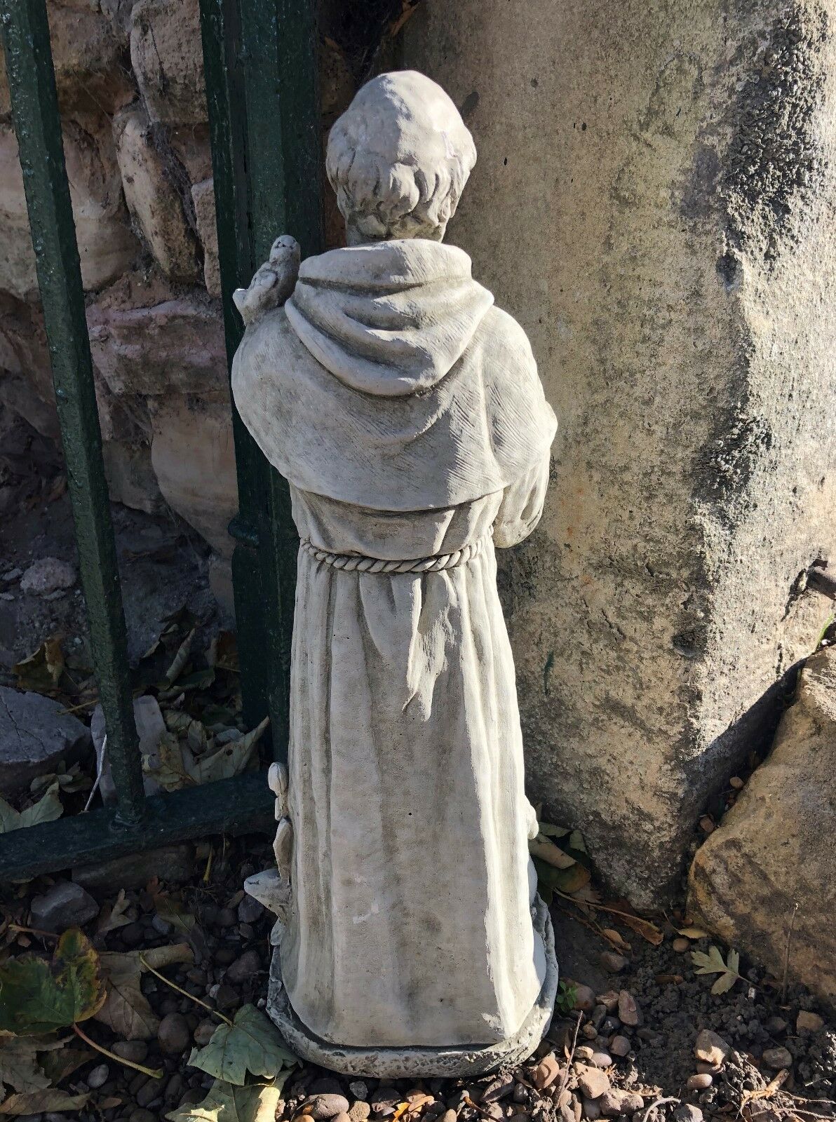 Rear view of St Francis stone statue with rope belt detail. Durable garden sculpture designed to withstand outdoor elements year-round.