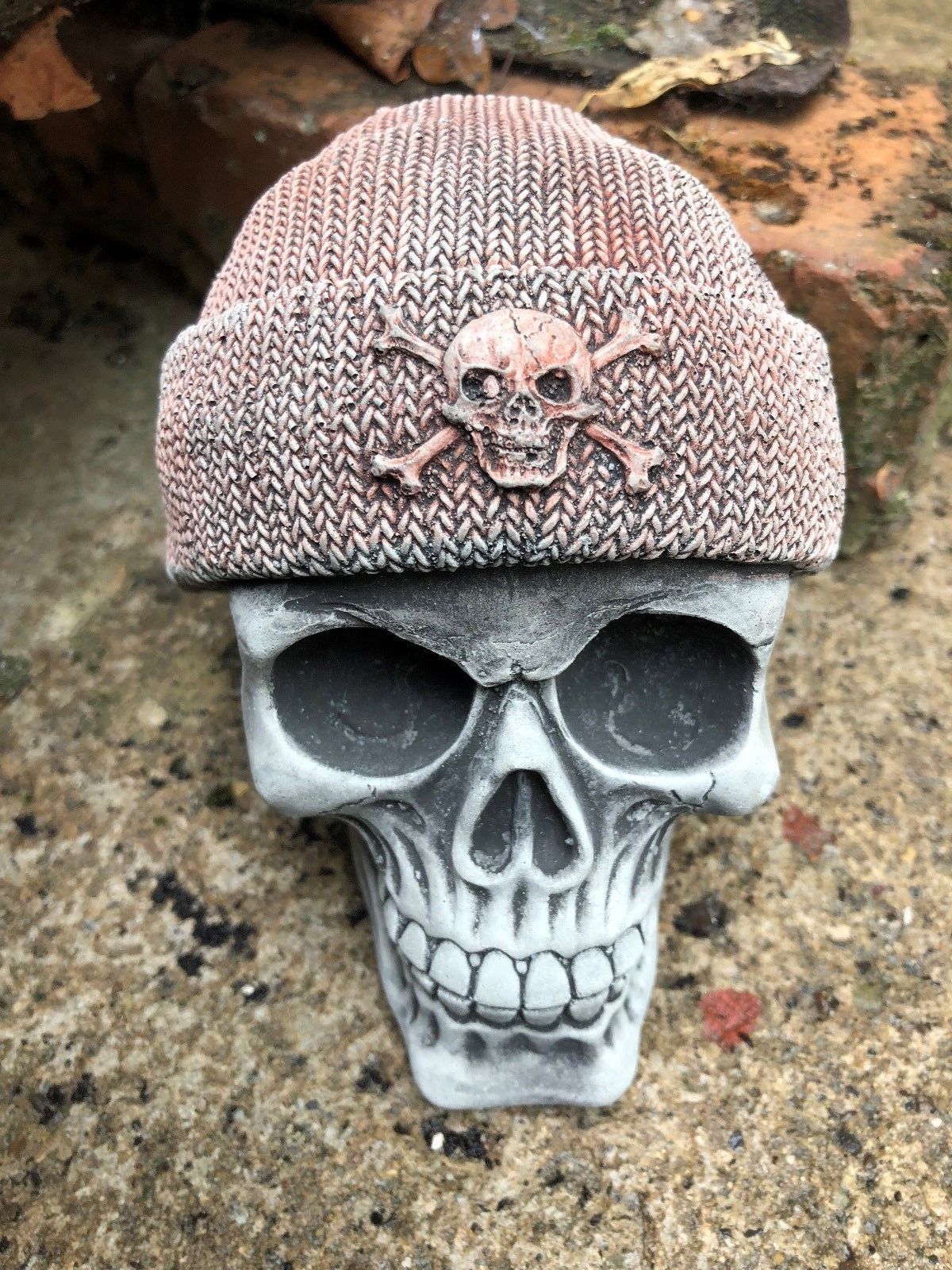 Close-up of Stone Skull Beanie Ornament with skull-and-crossbones emblem on beanie, a striking limestone sculpture for outdoor garden styling.
