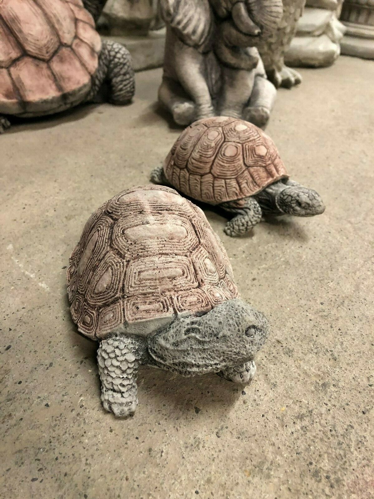 Stone tortoise garden decor pair positioned on concrete surface, showcasing realistic design and antique-style finish for home and lawn use.