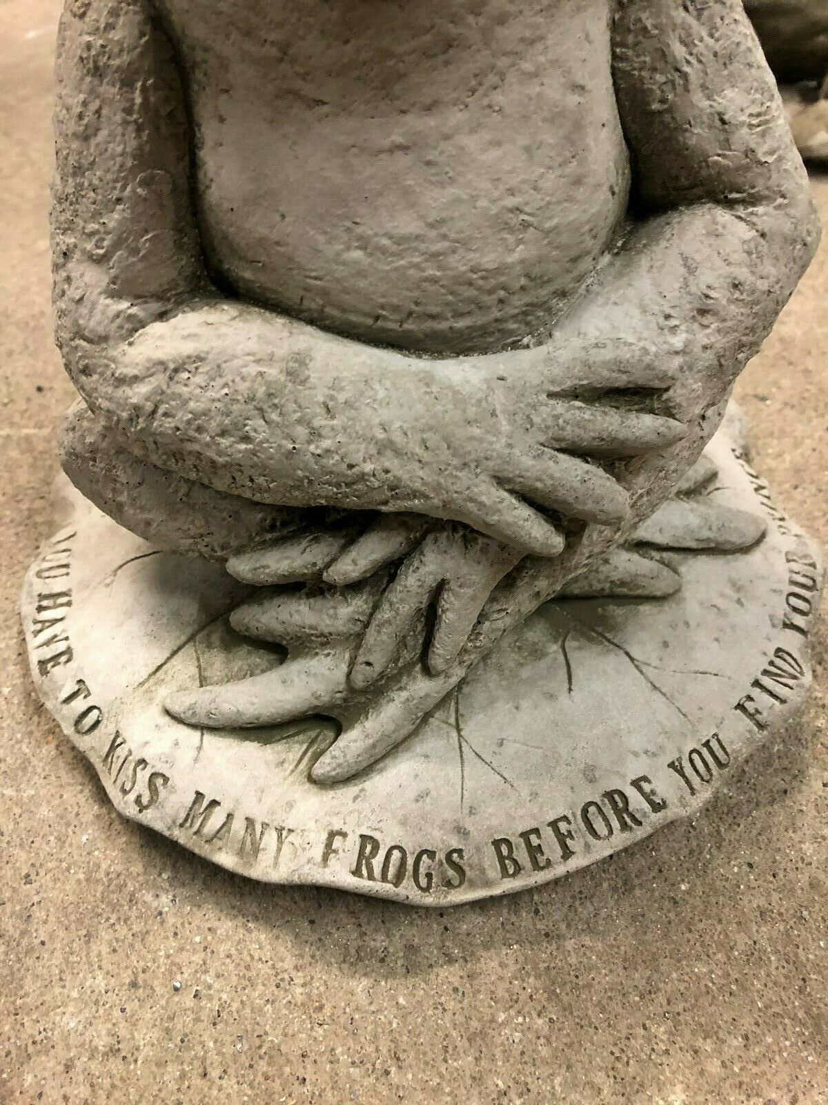 Detailed view of the base of the Stone Frog on Lilypad Ornament showing engraved quote 'You have to kiss many frogs before you find your prince.'