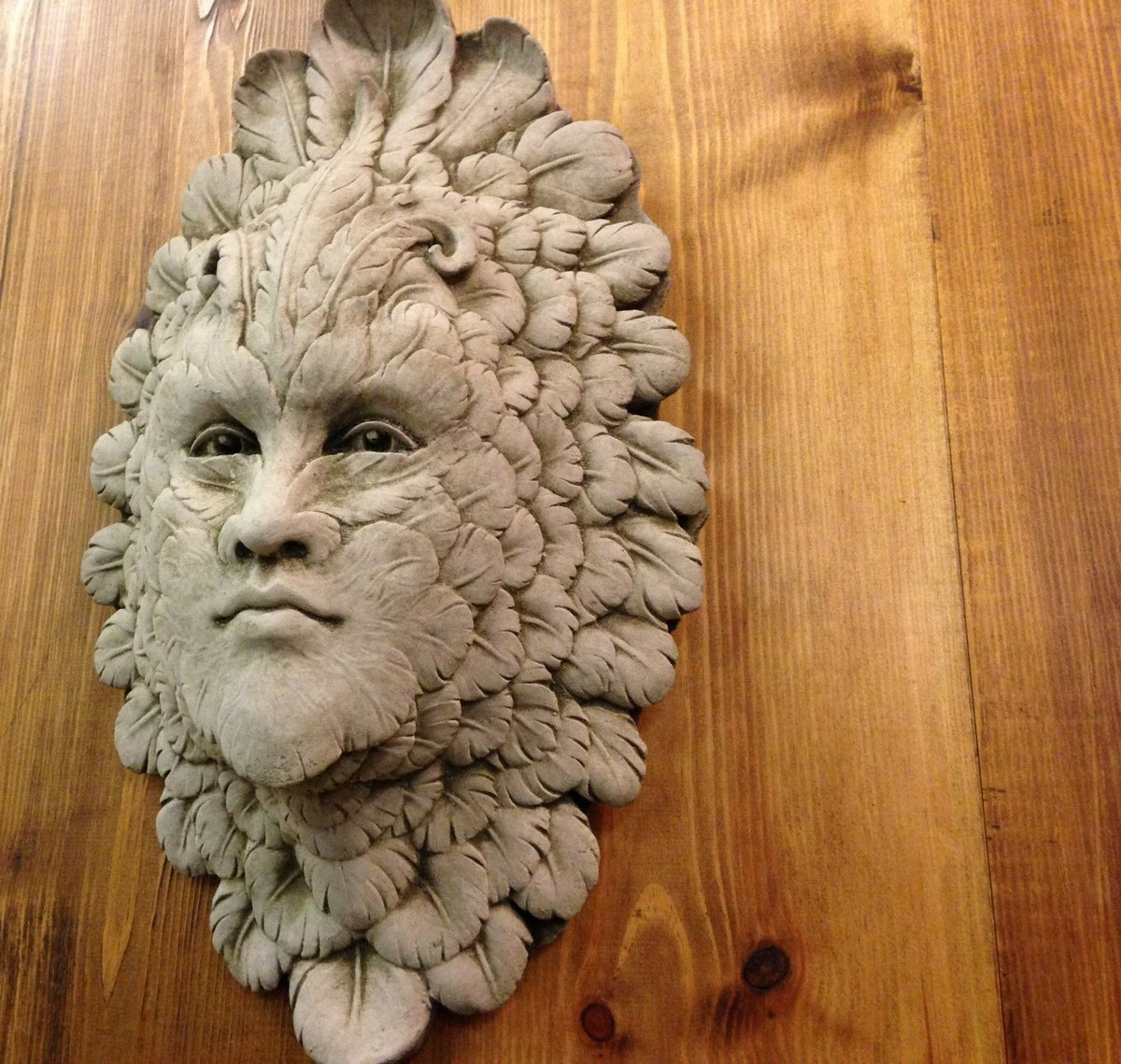 Greenman Garden Wall Plaque - Stone Feather Face mounted on wood panel. Mythical limestone ornament with detailed leaf and feather design.