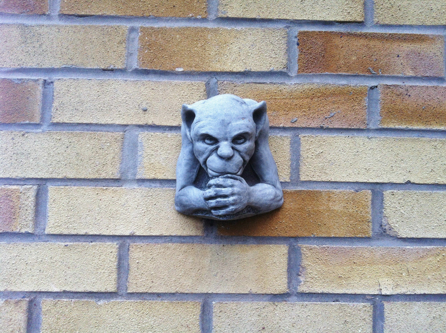 Gargoyle Garden Ornament fixed on brick wall. Antique limestone stone sculpture perfect for gothic garden or home wall decor.