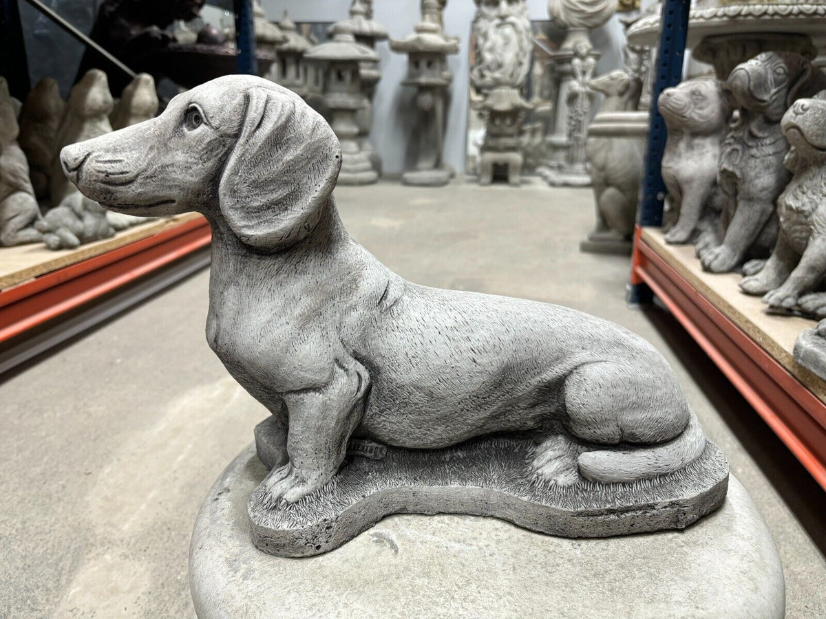 Sausage Dog Garden Ornament in stone finish, ideal for outdoor decor. Weatherproof dachshund statue adds charm to lawns and patios.