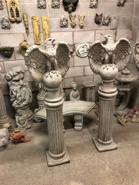 Pair of unique stone eagle garden statues on tall fluted limestone pedestals, ideal for outdoor decor in classic or antique-style gardens.