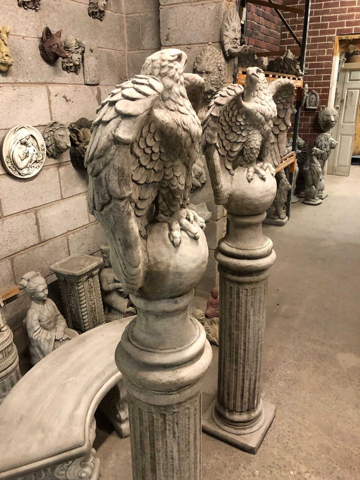 Side profile of stone eagle statues on tall limestone pedestals, ideal for antique-themed garden or patio decor.