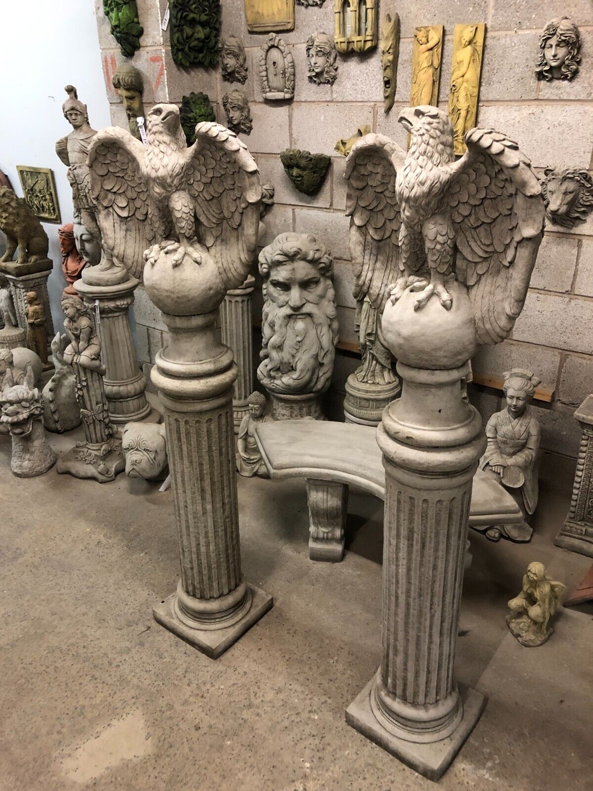 Side angle of handcrafted stone eagle statues on classical columns, showcasing intricate feather detailing for elegant garden sculpture decor.