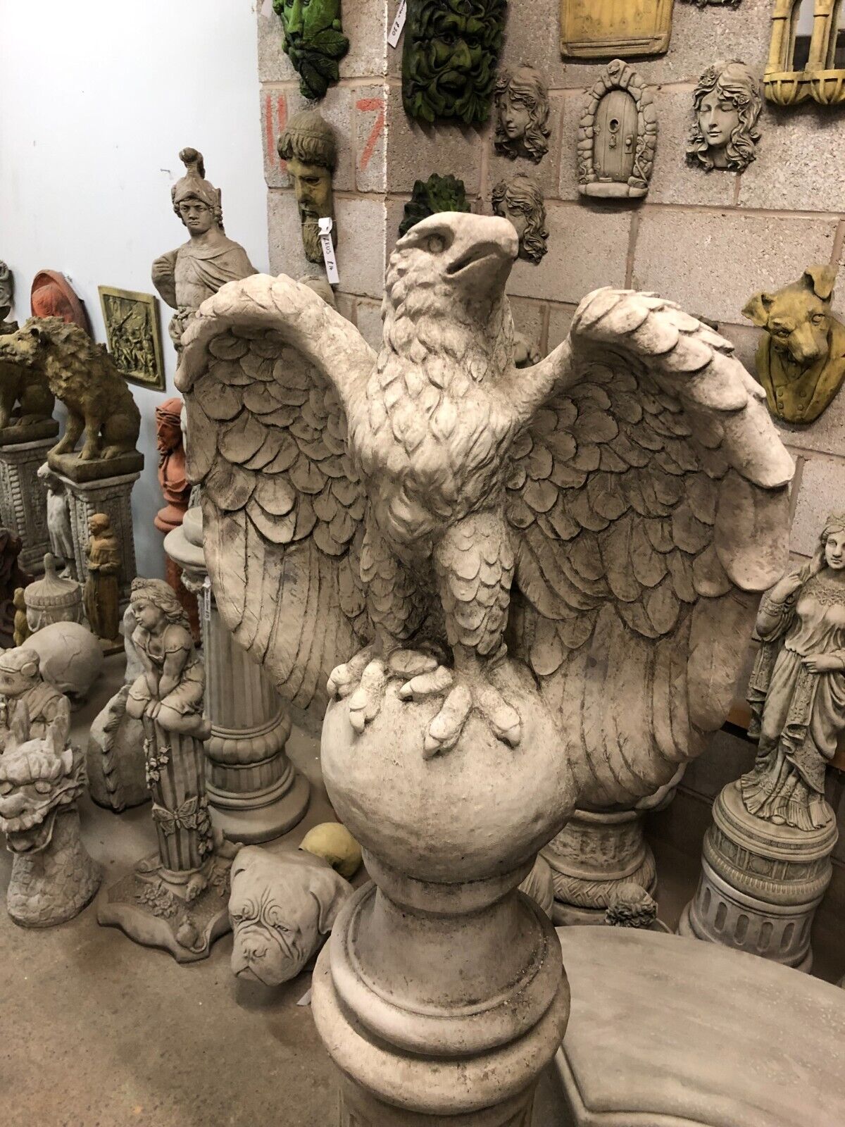 Detailed view of a single limestone eagle statue with open wings, perched on a round base, perfect for garden sculpture collections.
