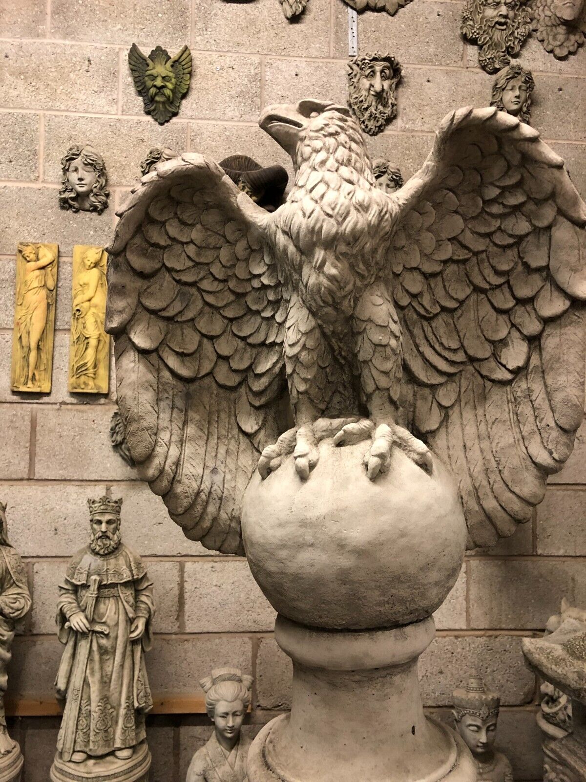 Back view of limestone eagle statue with detailed feather texture, mounted on a classic column for timeless outdoor decor.