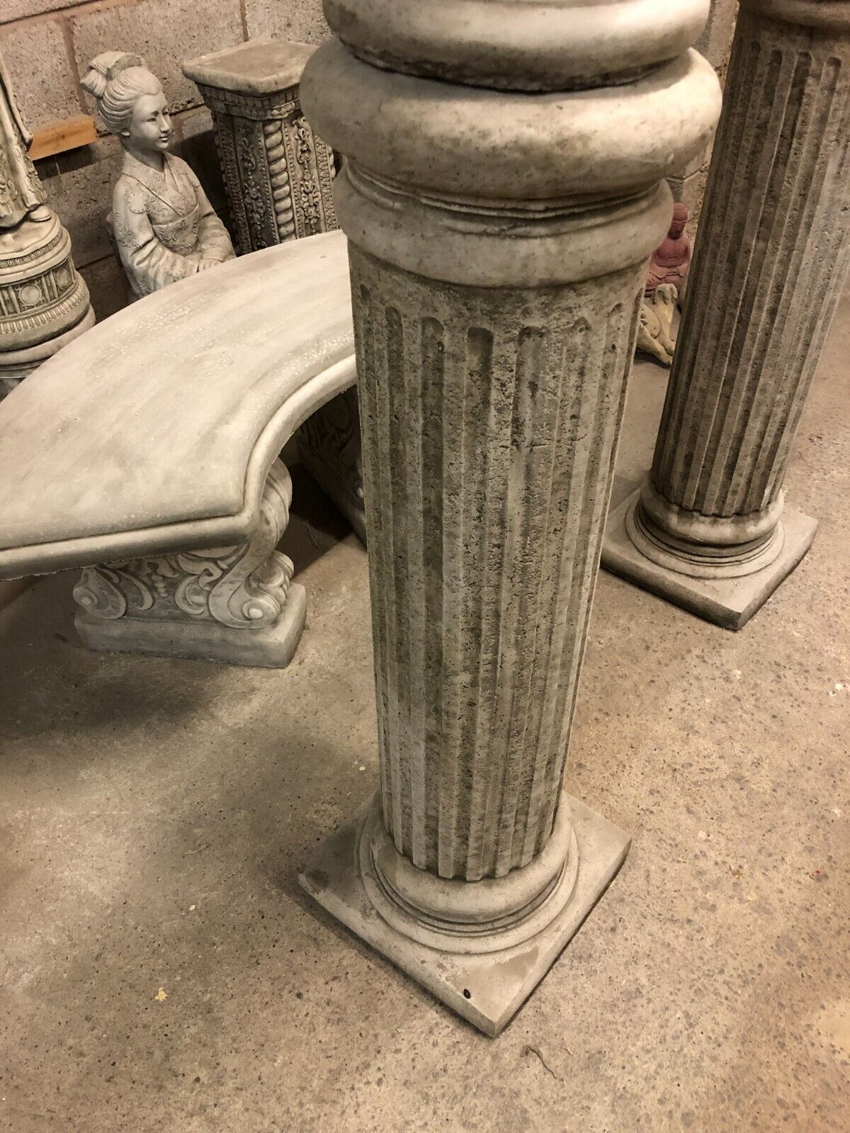Base of fluted limestone pedestal supporting eagle statue, showcasing durable stonework for long-lasting garden use.