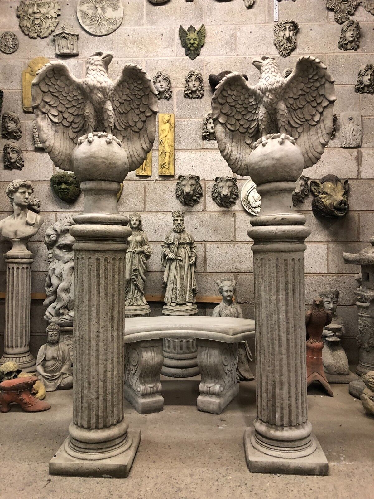 Rear view of limestone eagle statues with detailed wings, perched on stone columns, perfect for enhancing garden entrances or patios.