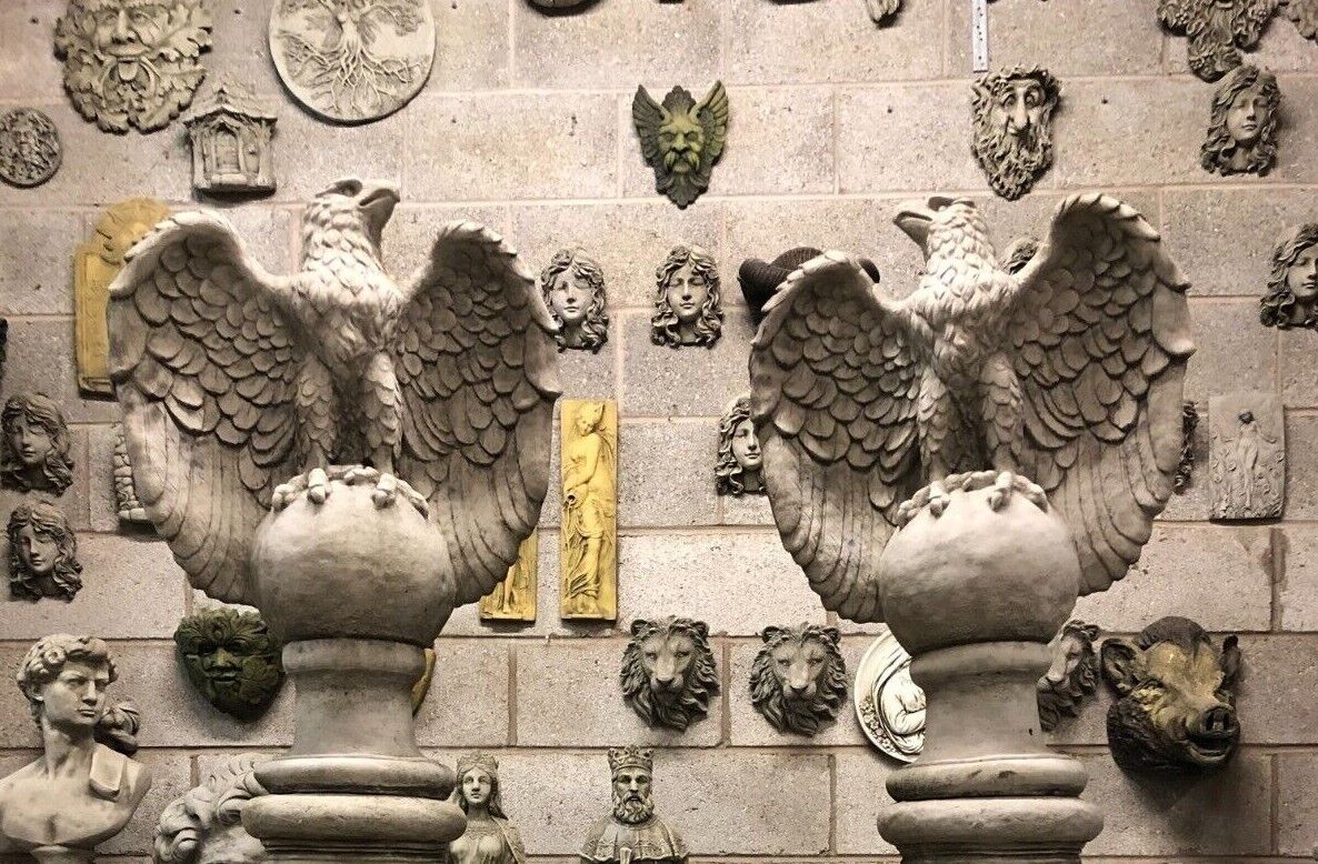 Top view of two limestone eagle statues with wings spread, mounted on stone columns, perfect for symmetrical garden entrance decor.