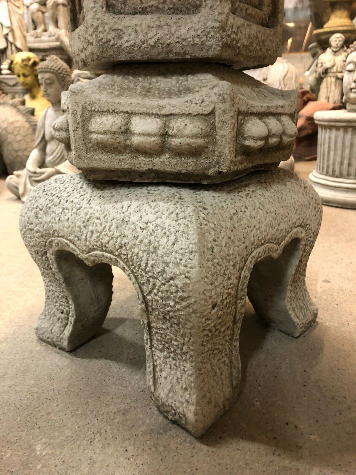 Detailed view of the lantern base showing textured limestone craftsmanship and stable design for outdoor garden placement.