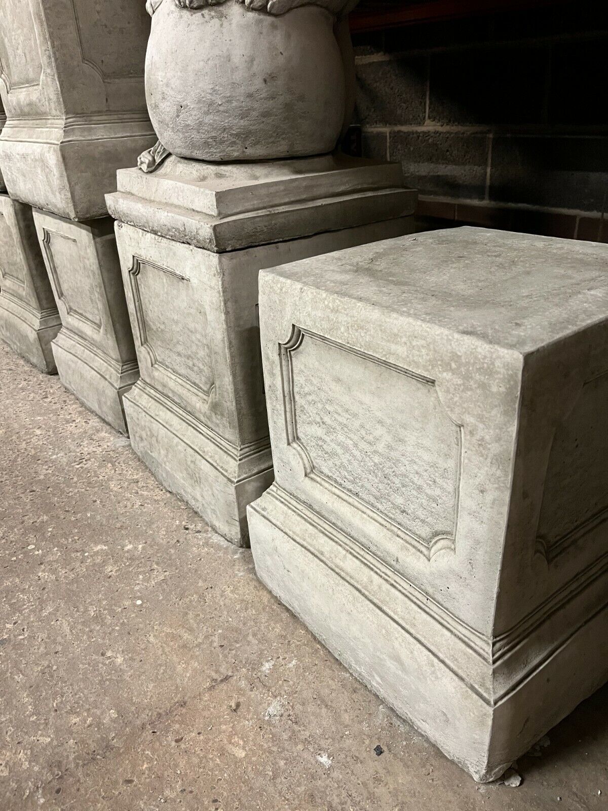 Multiple large stone garden plinths with antique-style paneling, designed for elevating statues or planters in home or garden settings.
