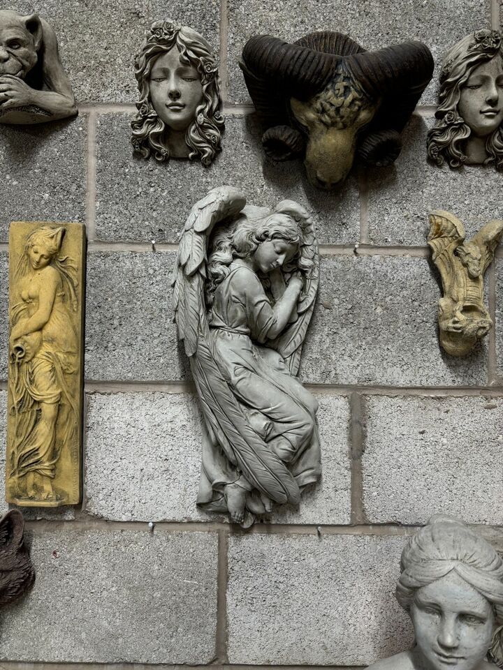 Full wall display featuring the Winged Angel Garden Plaque among other sculptures, emphasizing its size and decorative appeal.