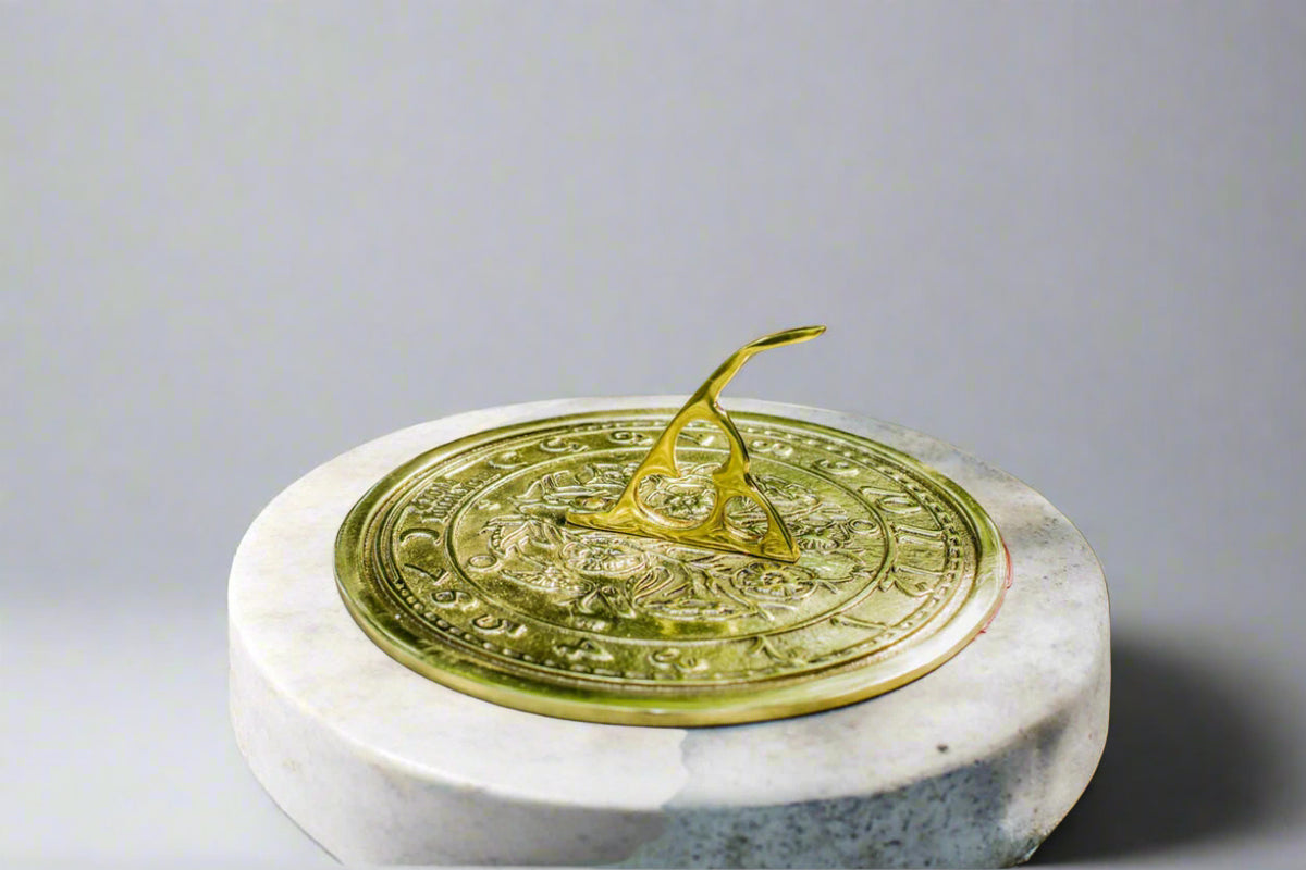 Close-up of bronze sundial plate with ornate carvings atop a reconstituted stone pedestal, part of a durable classical garden sundial plinth.