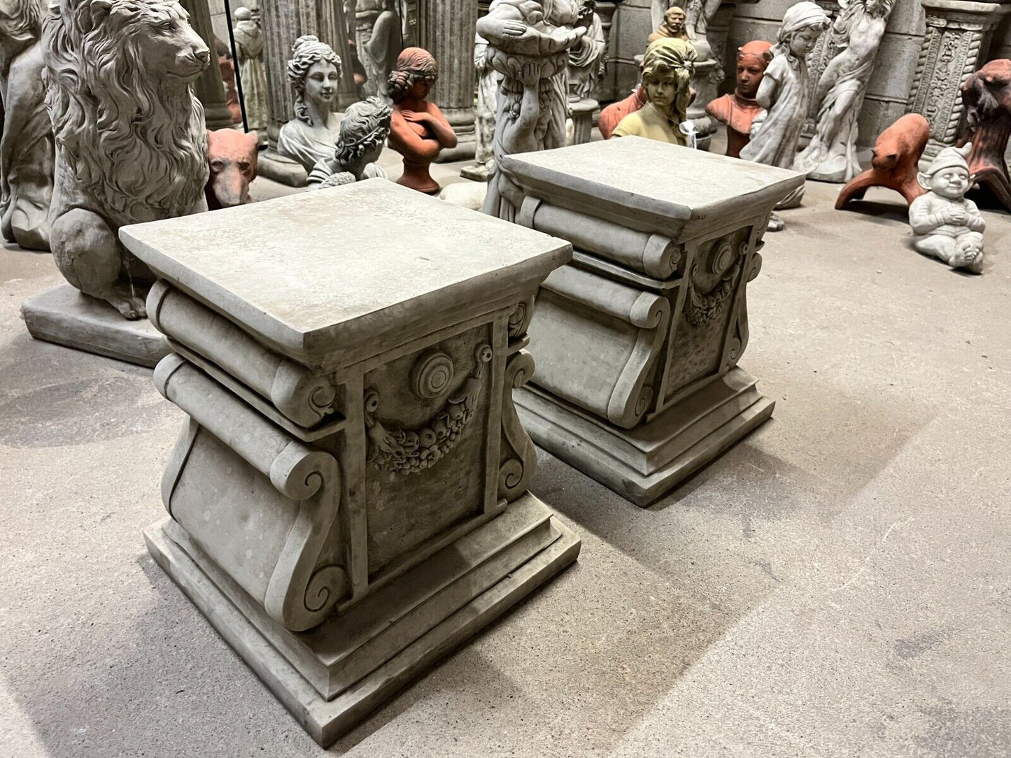 Decorative 38cm grey stone plinths with classical garland carvings, perfect for showcasing sculptures in outdoor garden settings.