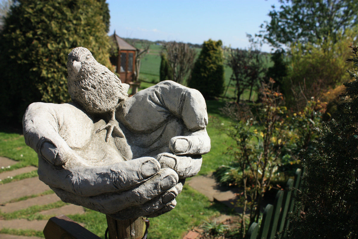 Bird Bath/Feeder - Stone Hands Design with Durable Finish mounted on a garden post, featuring lifelike bird sculpture and limestone texture.
