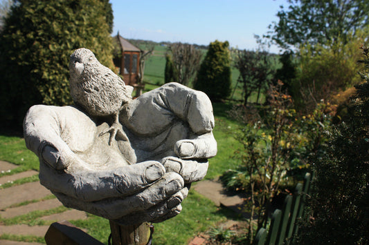 Bird Bath/Feeder - Stone Hands Design with Durable Finish mounted on a garden post, featuring lifelike bird sculpture and limestone texture.