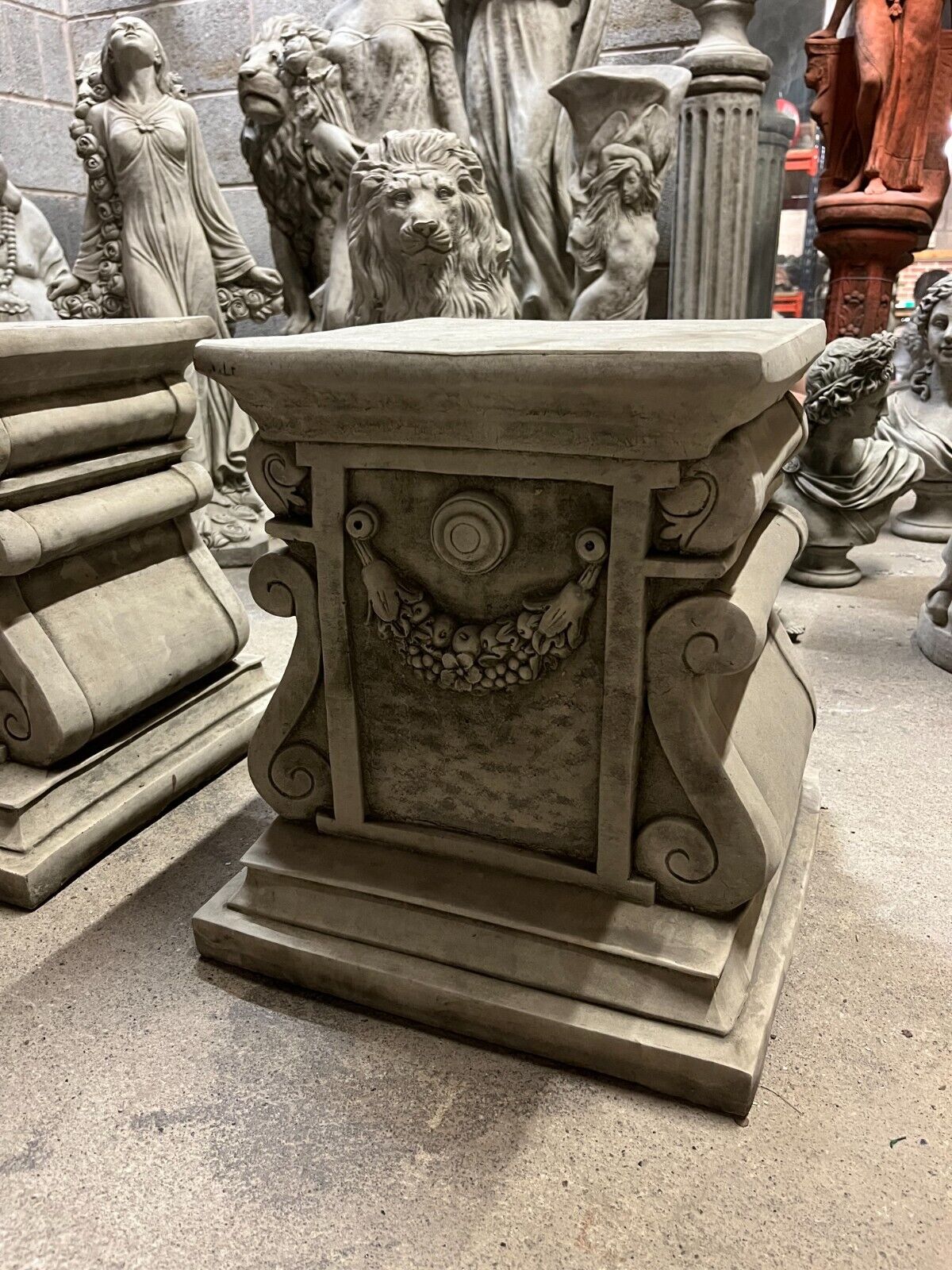 Close-up of floral garland detail on garden stone plinths, showcasing traditional craftsmanship for elegant outdoor decor.