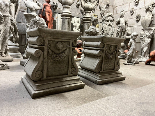 Pair of antique-style garden stone garland plinths with floral swag detail, ideal for elegant statue display in home or garden decor.