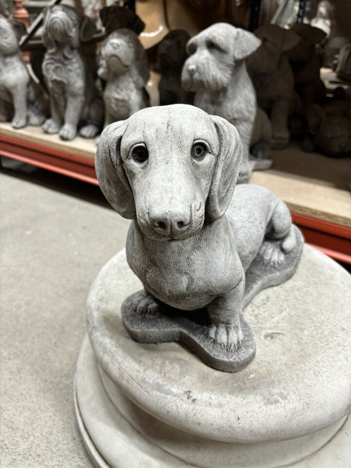 Front view of Stone Sausage Dog Garden Ornament showing realistic facial features. A charming weatherproof addition to garden decor.