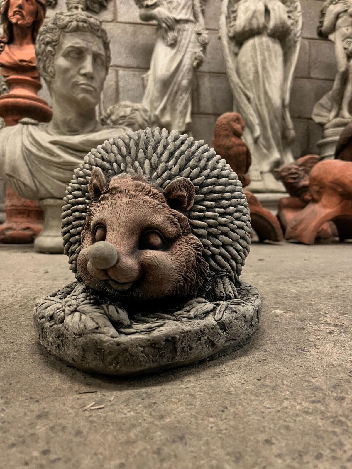 Charming Stone Hedgehog Garden Ornament with textured spines and smiling face. Ideal for whimsical lawn decoration or patio display.