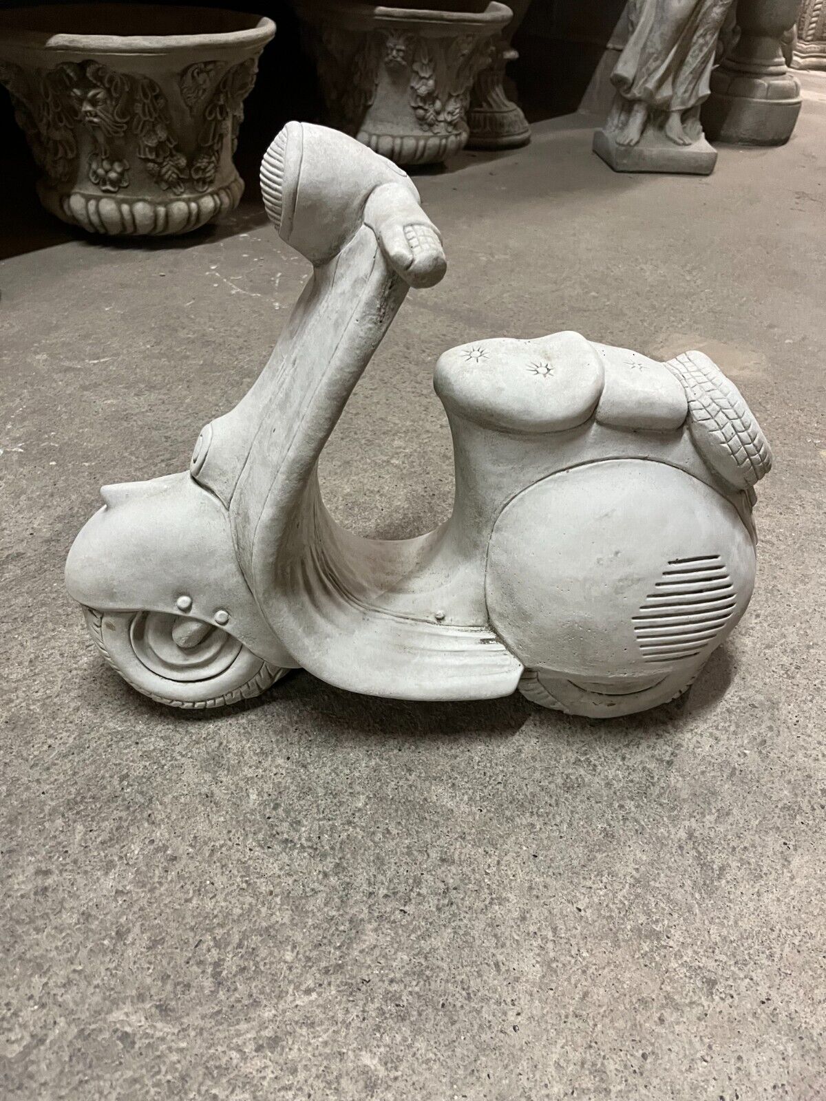 Side profile of Vesper Motorbike Garden Ornament showing intricate limestone detailing and antique grey stone texture for garden display.