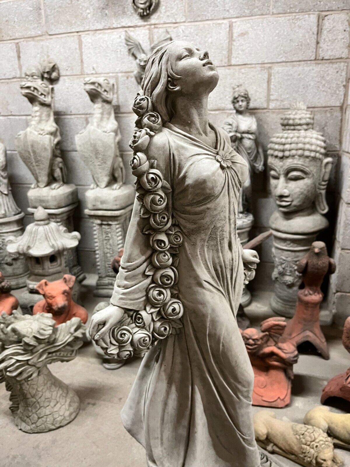 Side profile of elegant garden statue with stone roses and graceful posture, ideal for enhancing garden aesthetics.