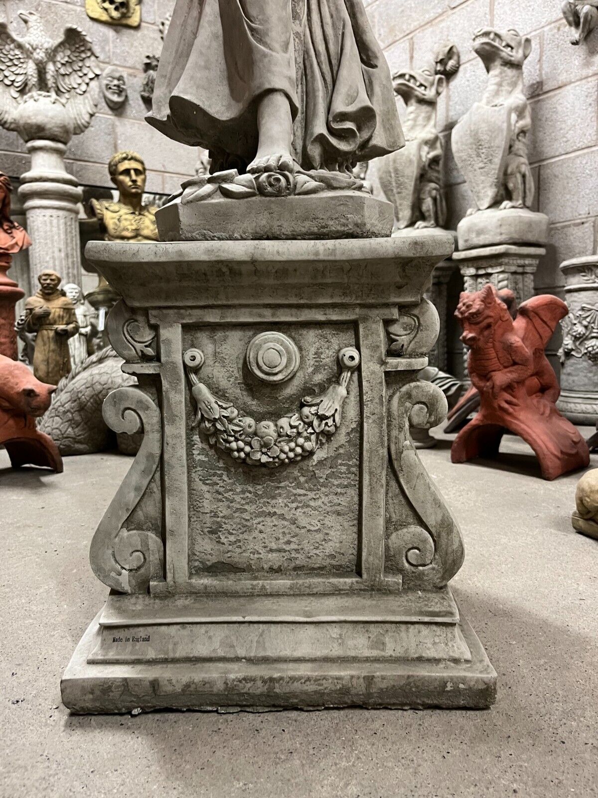 Base of Stone Rose Lady Statue with carved floral garland and scrollwork, highlighting its antique stone finish.