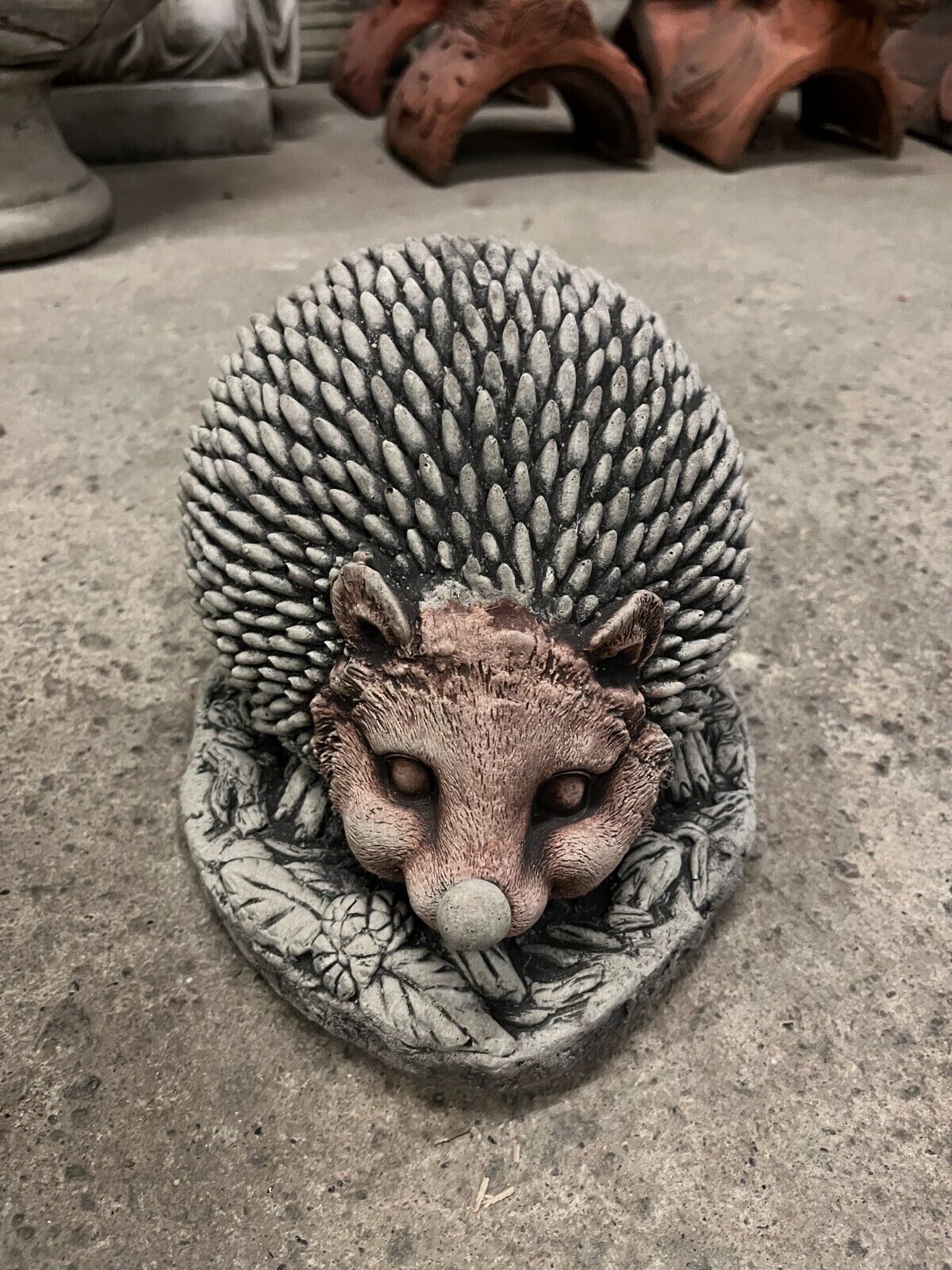 Front view of Unique Stone Hedgehog Garden Ornament with leaf base and antique finish. Adds personality to any garden or yard space.