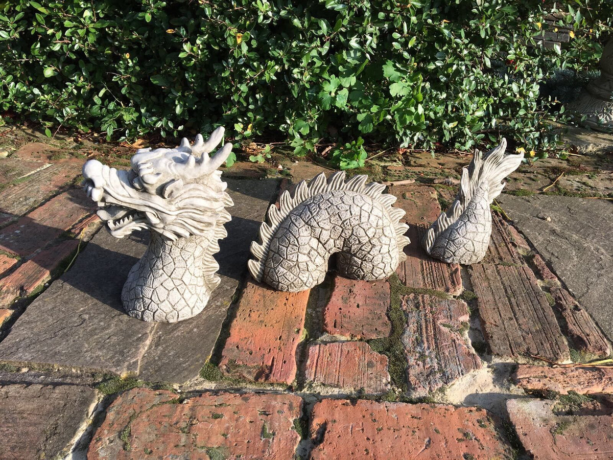 Stone Chinese Dragon Ornament for Elegant Garden Decor shown in three parts—head, body, and tail—on a rustic brick pathway with greenery.