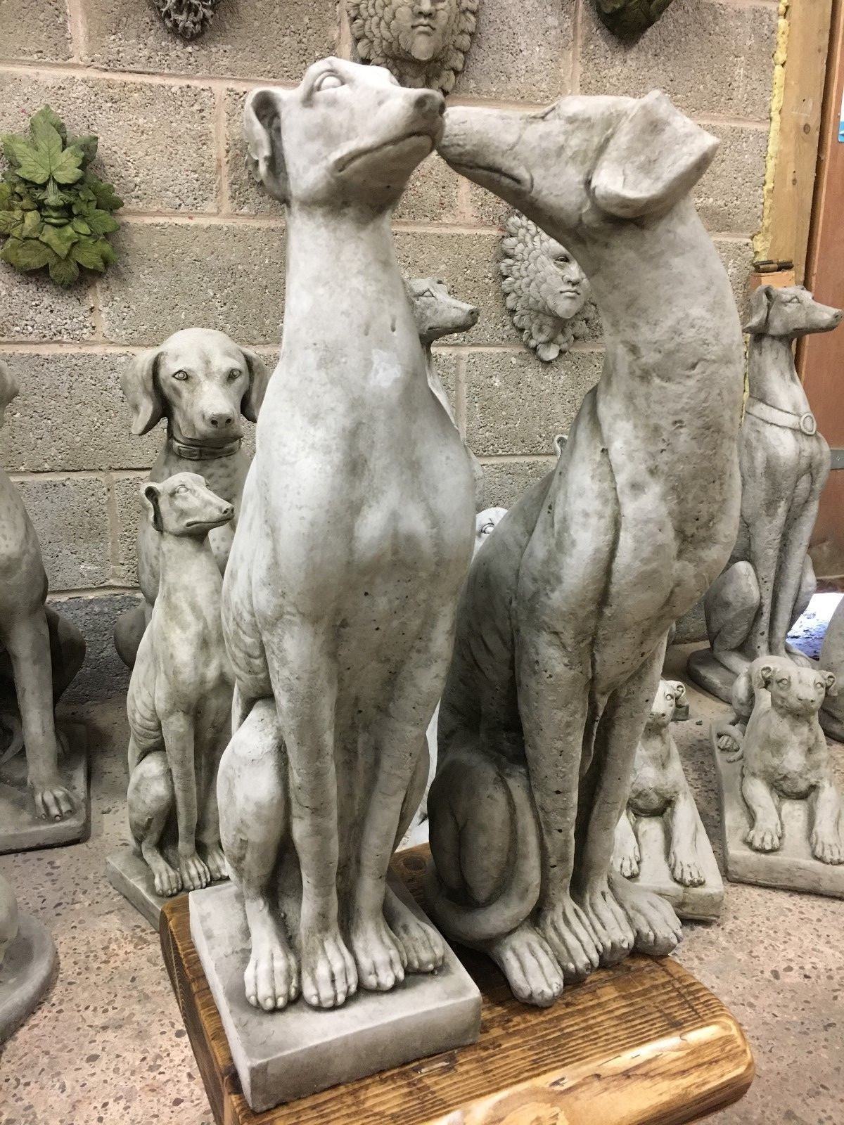 Two greyhound statues in affectionate pose, crafted from limestone for charming and durable garden sculpture.