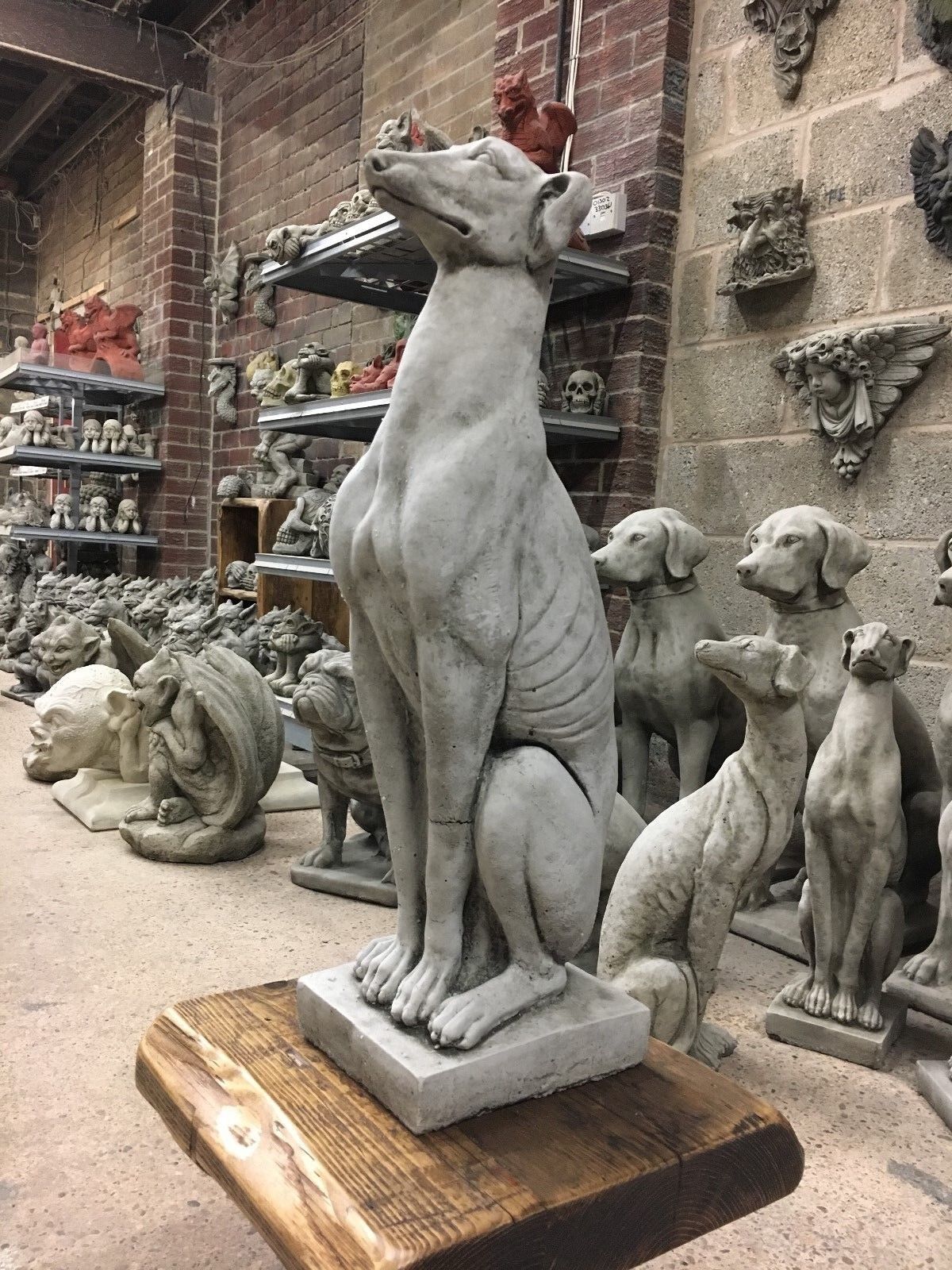 Tall greyhound statue in seated position on wooden base, made from solid limestone for durable and elegant garden decor.