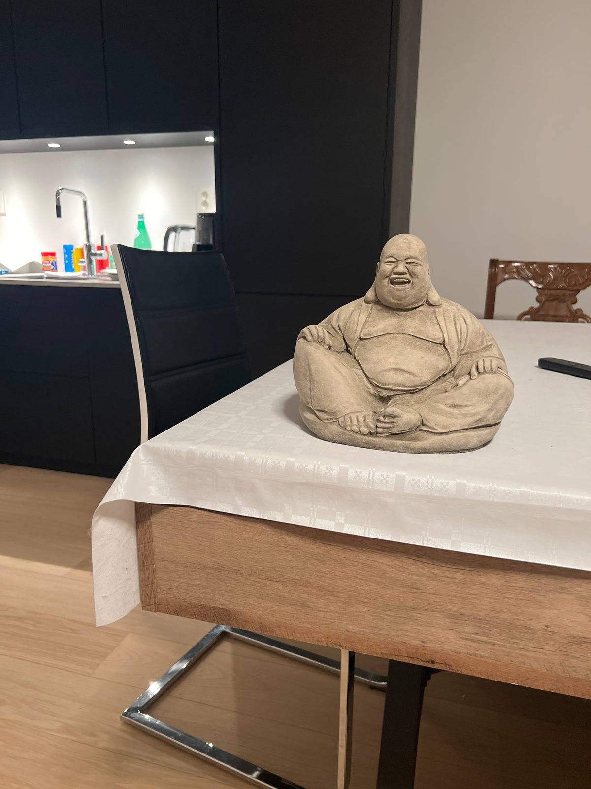 Stone Laughing Buddha Ornament displayed indoors on a dining table, showing its versatility for both indoor and outdoor zen decor.