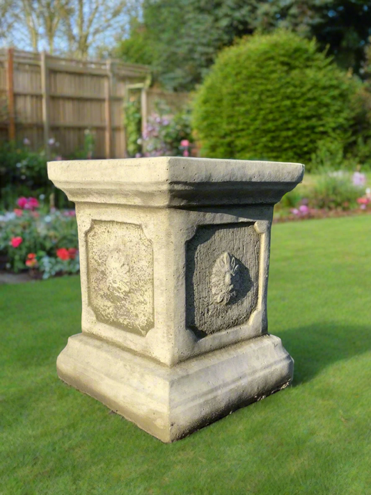 Elegant stone garden plinth with carved floral detail, ideal for small design displays in outdoor lawn or garden décor settings.