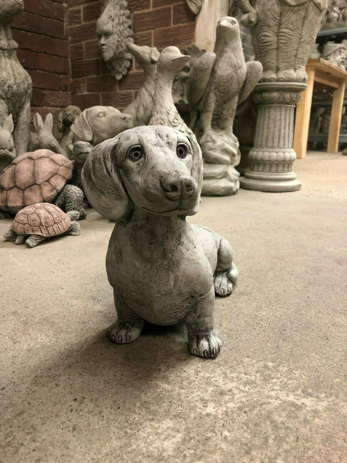 Front view of Stone Sausage Dog Garden Ornament with antique finish, ideal for patios, lawns, or flowerbeds.