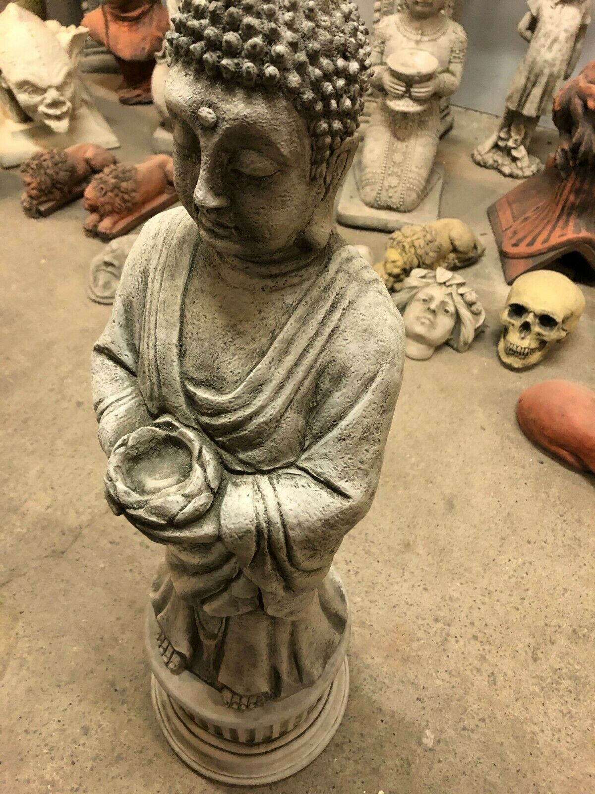 Close-up of Buddha statue's hands holding a candle bowl, showcasing intricate stone detailing and craftsmanship.
