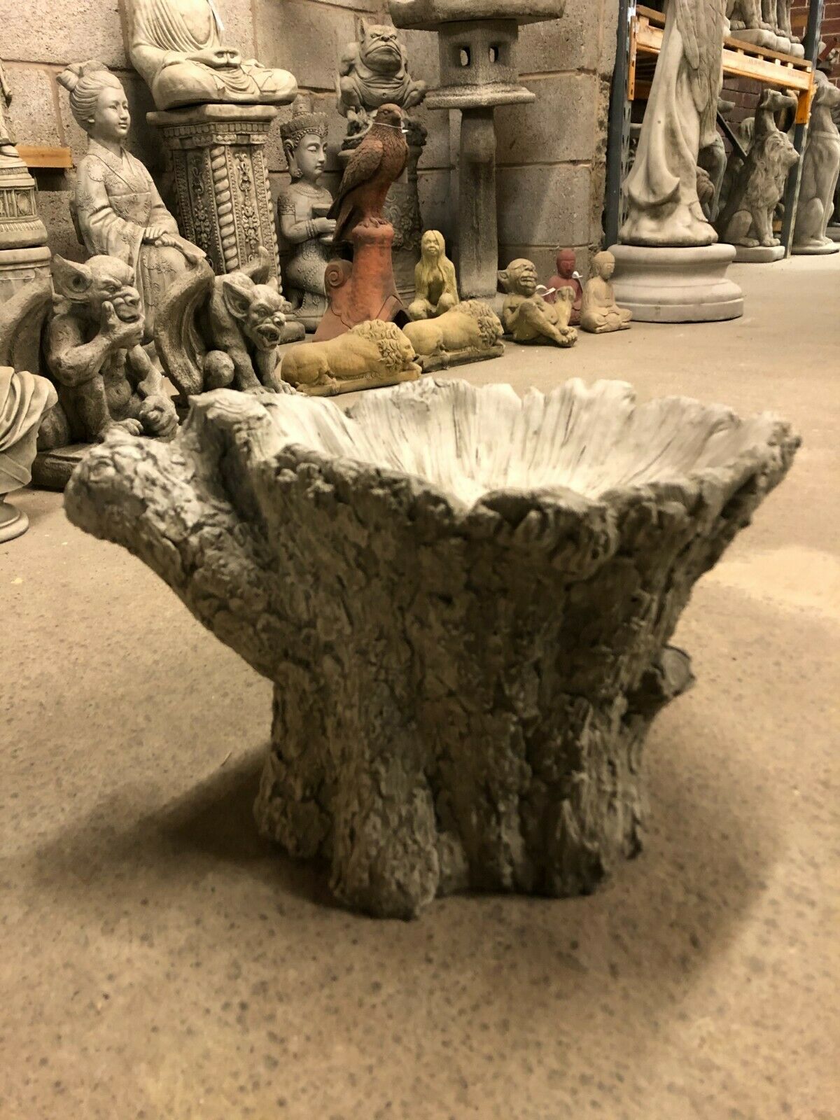 Side view of stone tree stump bird bath with realistic bark texture, designed as a durable and decorative garden ornament.