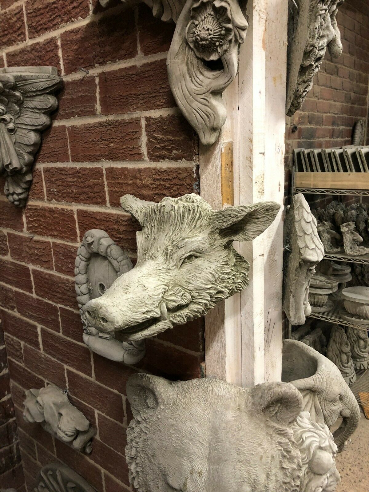 Angled view of Stone Wild Boar Wall Plaque with antique finish, mounted on a corner wall. Great for rustic garden or patio decoration.