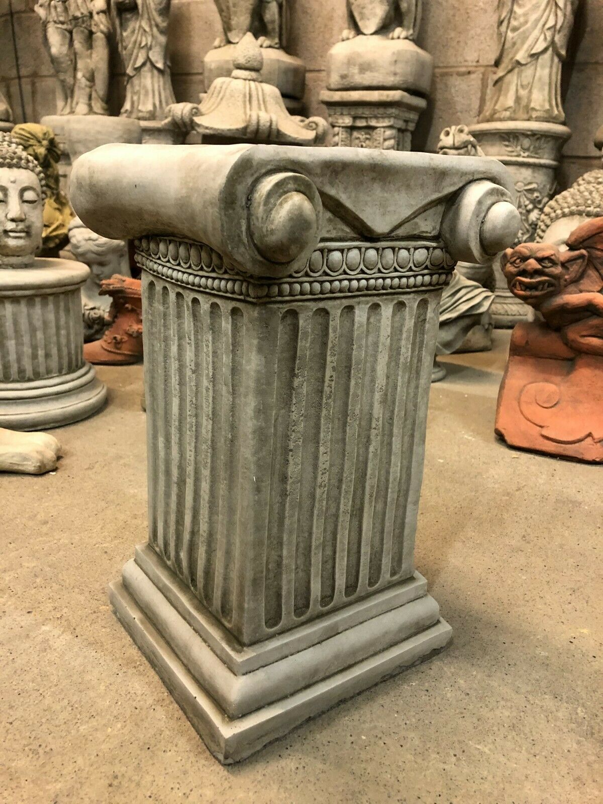 Durable Roman Garden Plinth in stone style with intricate scrollwork and fluted shaft, designed to elevate statues in outdoor settings.