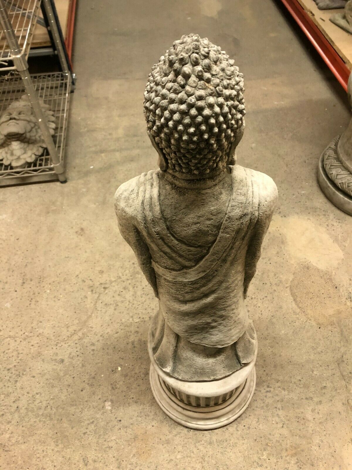 Rear view of stone Buddha garden statue highlighting textured hair and robe folds, suitable for outdoor decor.
